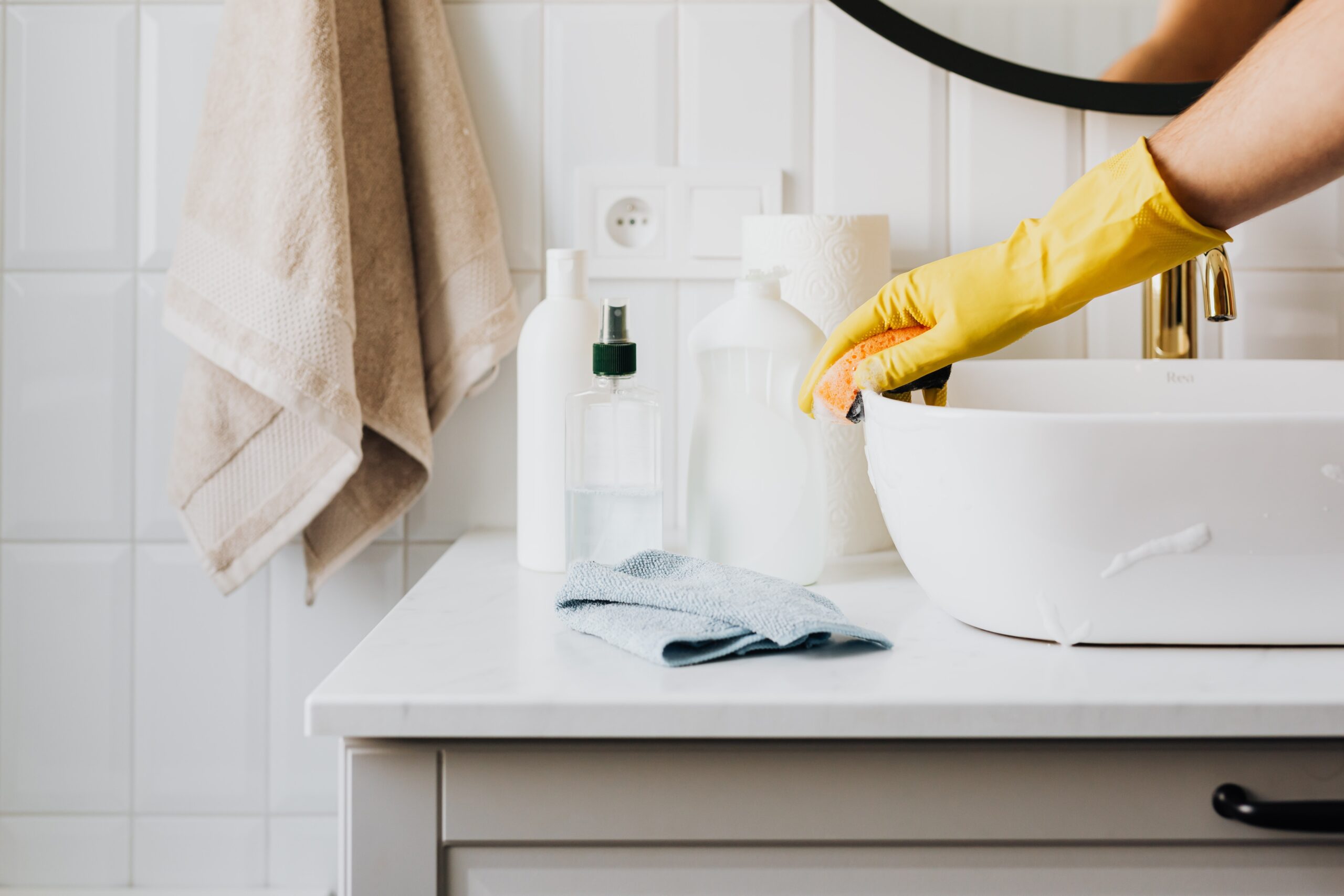 Woman's hand with gloves washing the sink